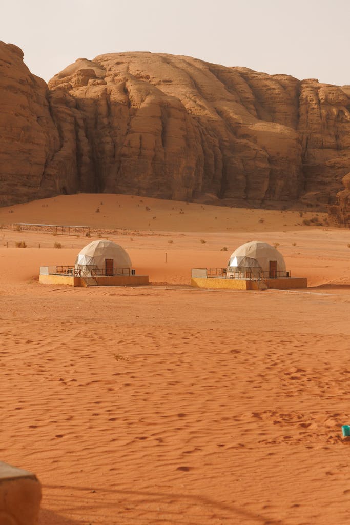 Desert view of geodesic domes surrounded by red sand and rocky formations in Wadi Rum, Jordan.